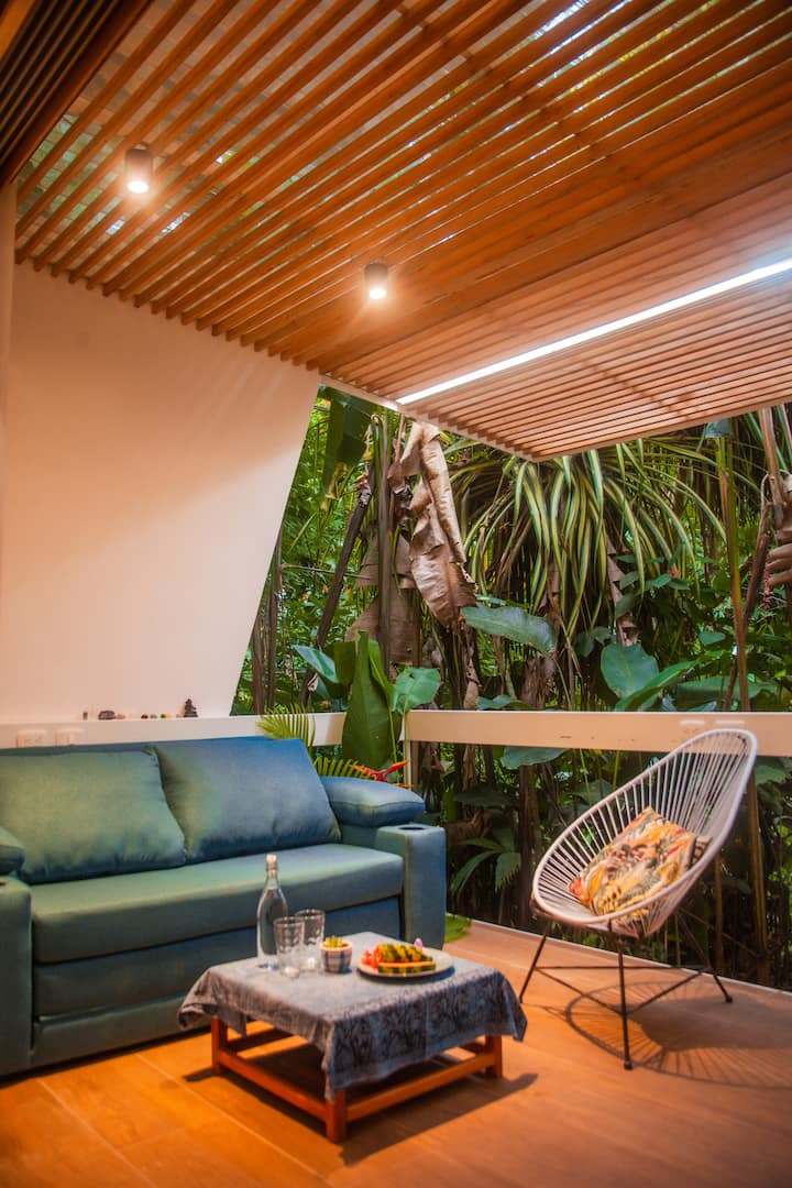 Terraza con sofá, mesa baja y silla frente a la selva